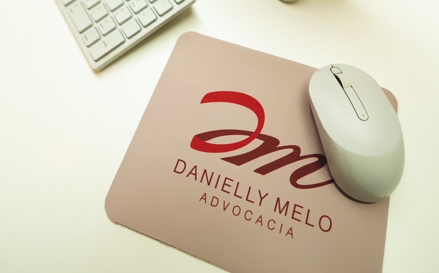 Mesa de trabalho do escritório, com o mousepad da Danielly Melo Advocacia
